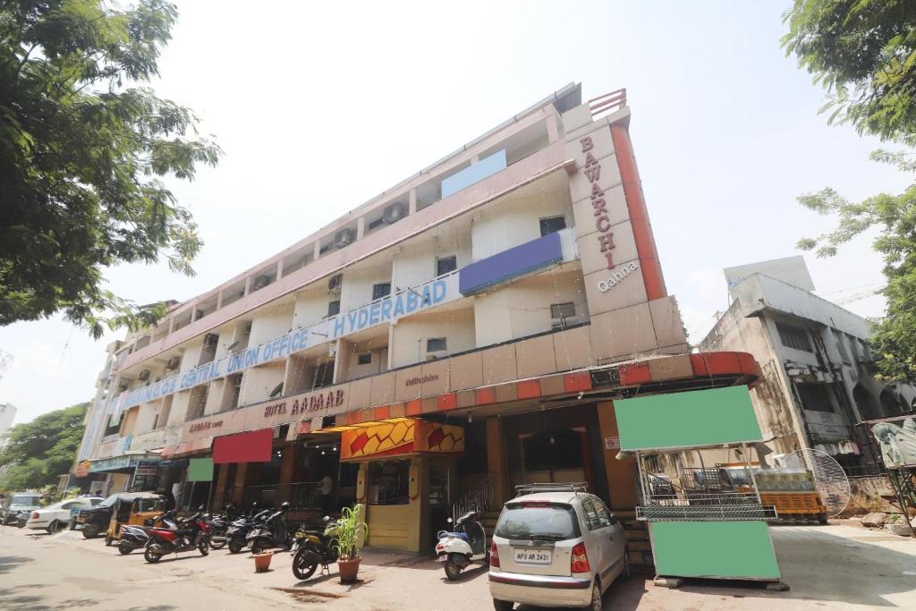a large building with cars parked in front of it at Hotel O Aadaab in Hyderabad