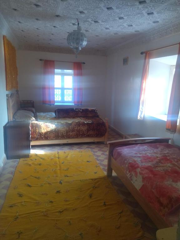 a bedroom with two beds and a yellow rug at Maison Ighrem in Idoukaln