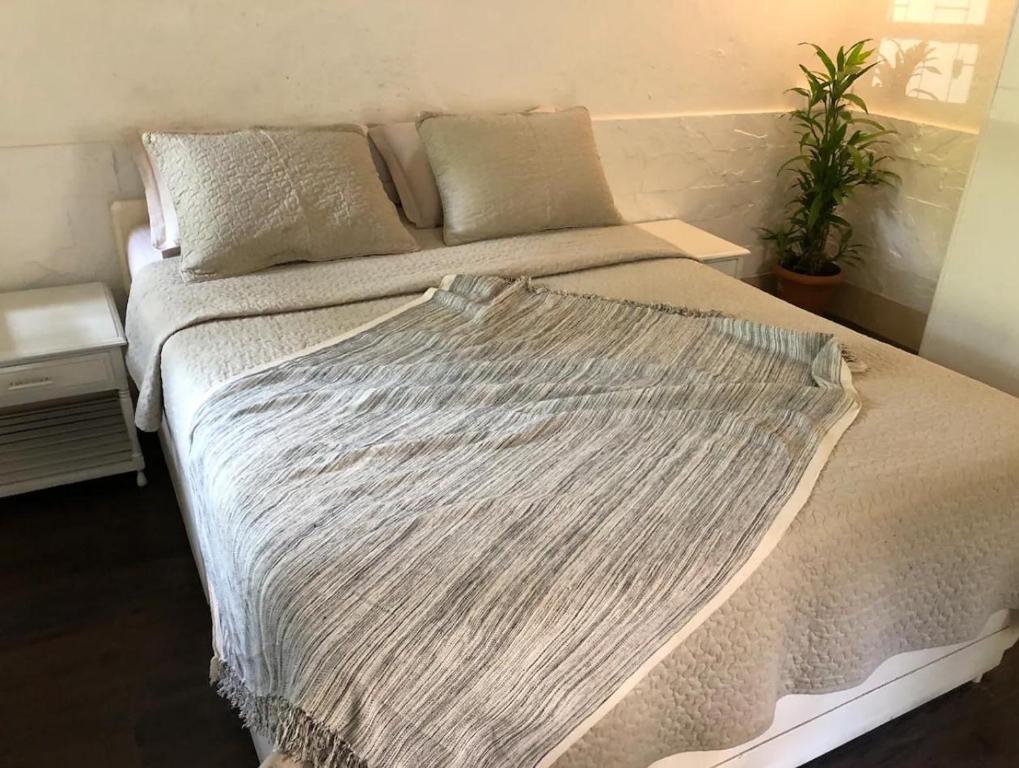 a bed with a white blanket on it in a bedroom at Cosy studio at Delphi bungalow in Mumbai