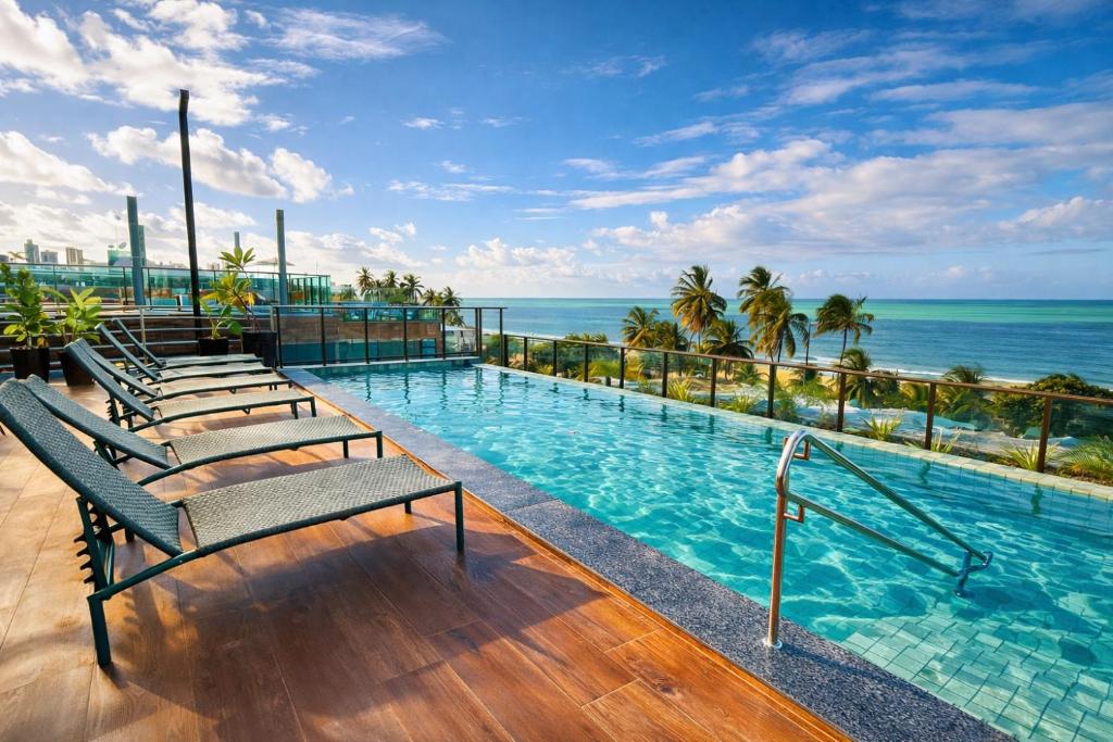 a swimming pool with a view of the ocean at Jardins Almare Apart Hotel in João Pessoa