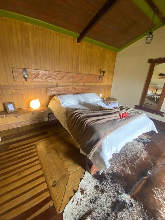 a large bed in a room with a wooden wall at Chalé Bougainville in Lavras Novas
