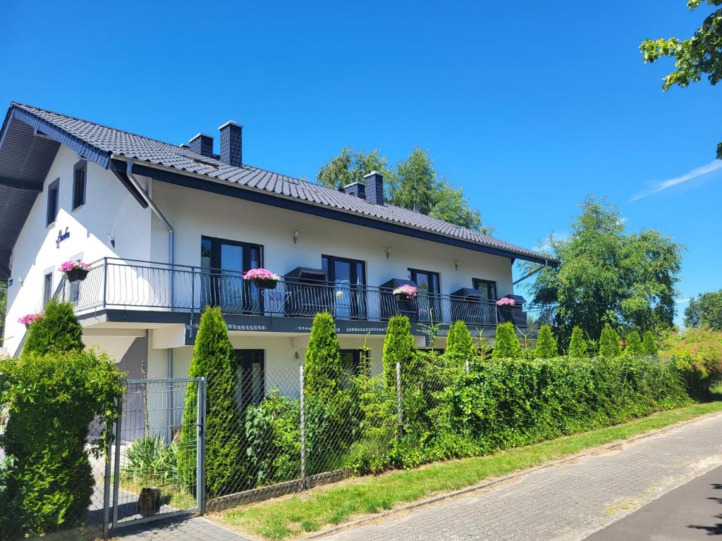 a white house with a balcony and bushes at Apartamenty Łuska Rowy in Rowy