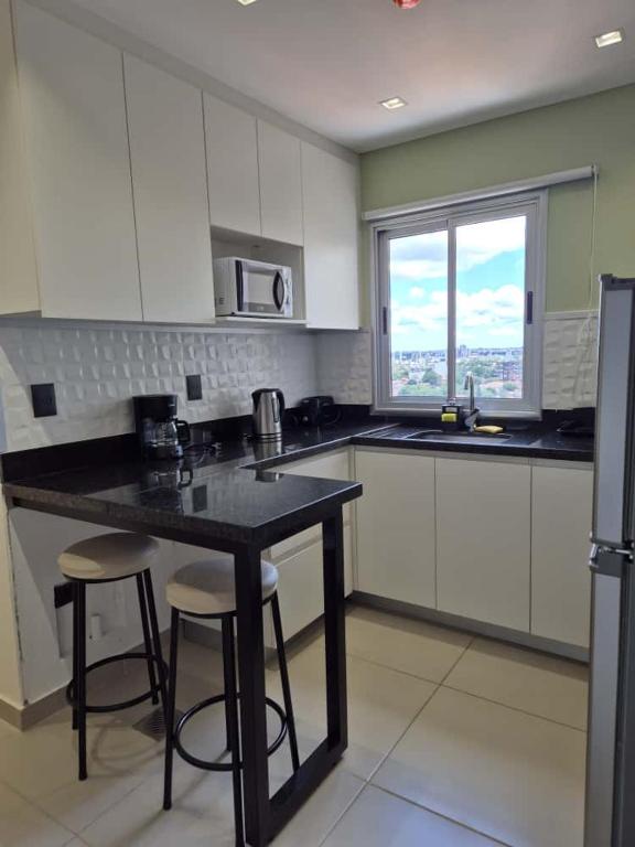 a kitchen with white cabinets and a black counter top at Molas 112B in Asunción