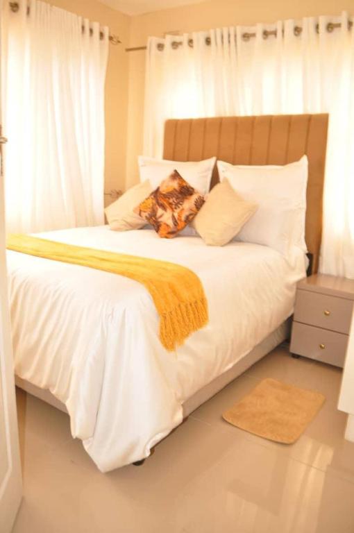 a white bed with white pillows and an orange blanket at RosiMug's Homestay in Umtali