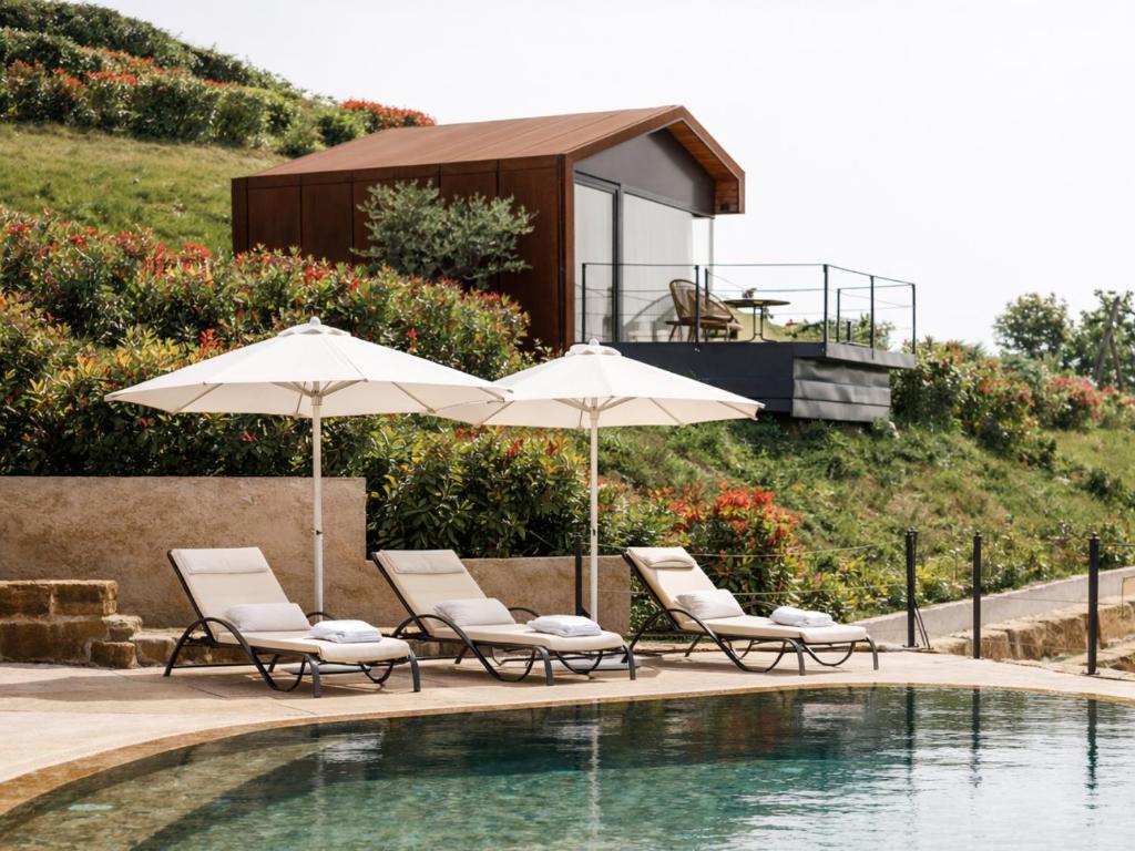 two chairs and umbrellas next to a swimming pool at Wine Paradise - Glamping resort in Marezige