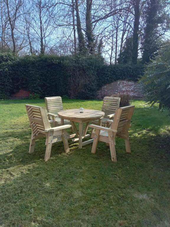 a picnic table with four chairs around it in the grass at 2 Bedroom Garden Flat in Halesworth
