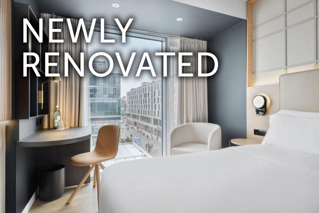 a hotel room with a bed and a view of a city at Barceló Dresden Newa in Dresden