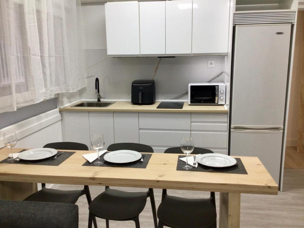 a kitchen with a wooden table with chairs and a refrigerator at Puerto playa B in Malpica