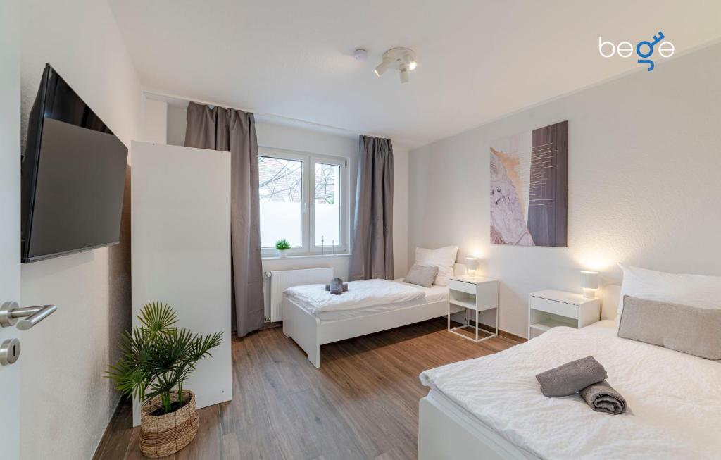a white bedroom with two beds and a window at BEGE APARTMENTS SmileStay in Gelsenkirchen