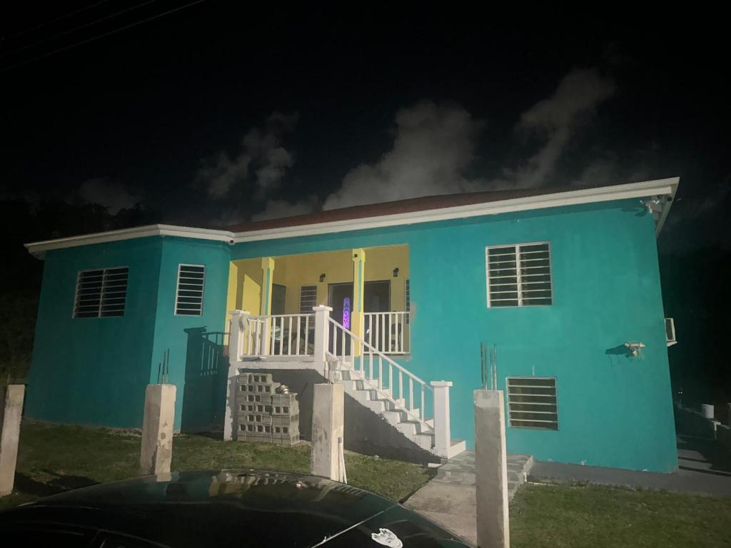 a blue house with a white porch at night at Hector residence in Saint Johnʼs