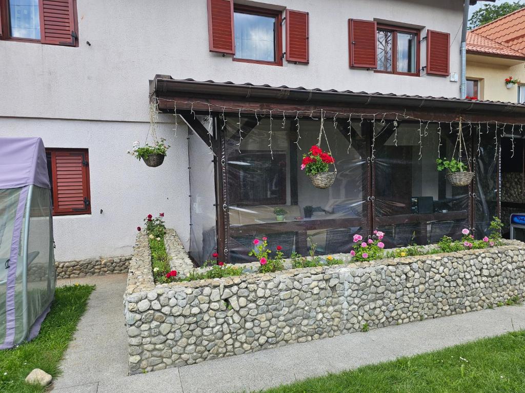 ein Haus mit Blumen in einer Steinmauer in der Unterkunft Forest Vila in Buşteni