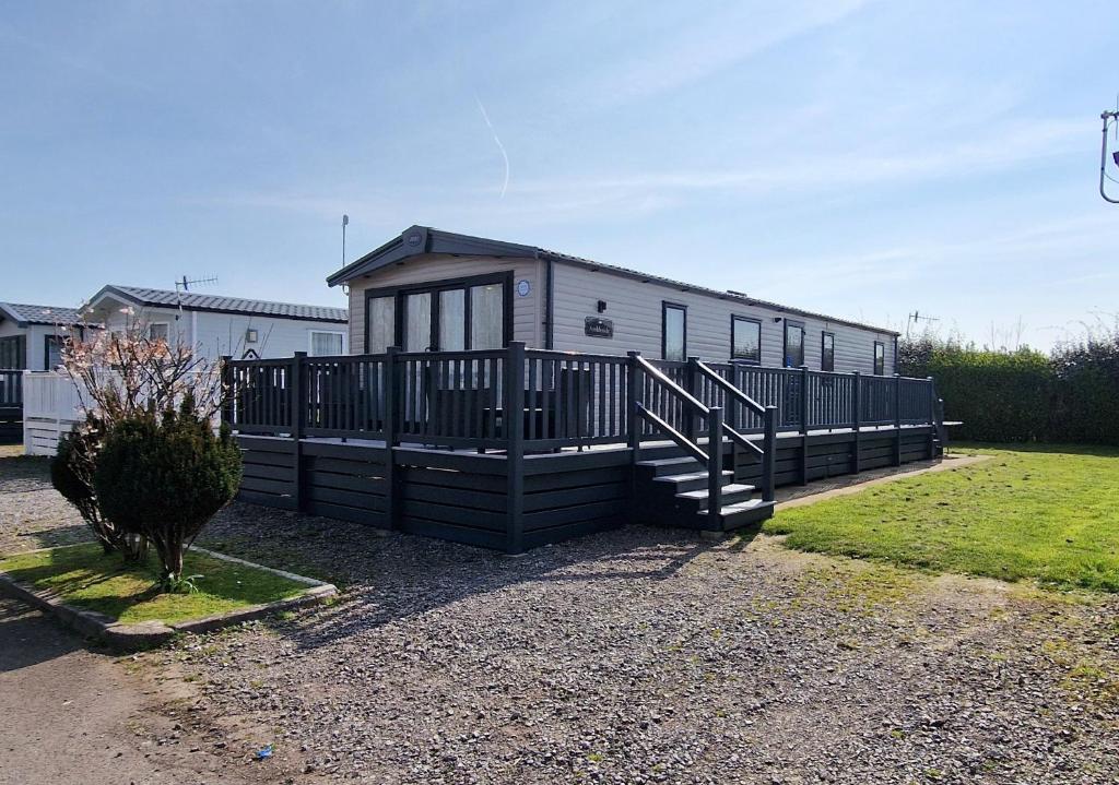 a black and white house with a porch and stairs at Rocco Family Retreat, Green Lawns in Selsey