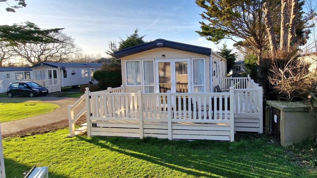 a small white shed with a white fence at Memories Made, Quiet Holiday, Green Lawns in Selsey