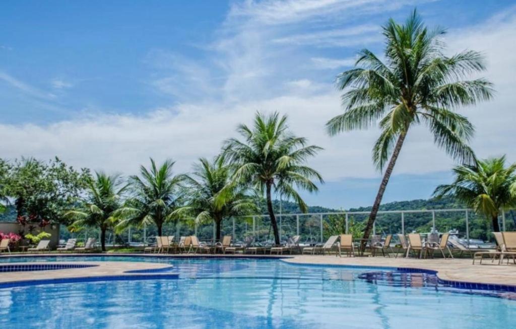 a pool at a resort with palm trees at Inefável flat Porto Marina Resort in Mangaratiba