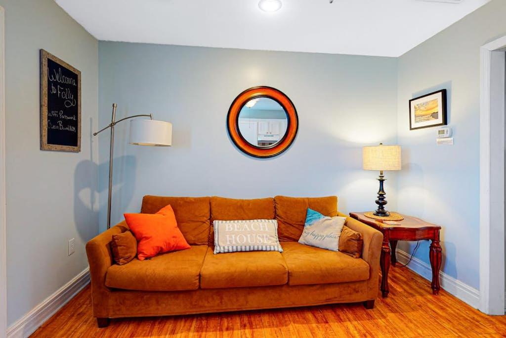 a living room with a brown couch and a mirror at Oceanbound in Folly Beach