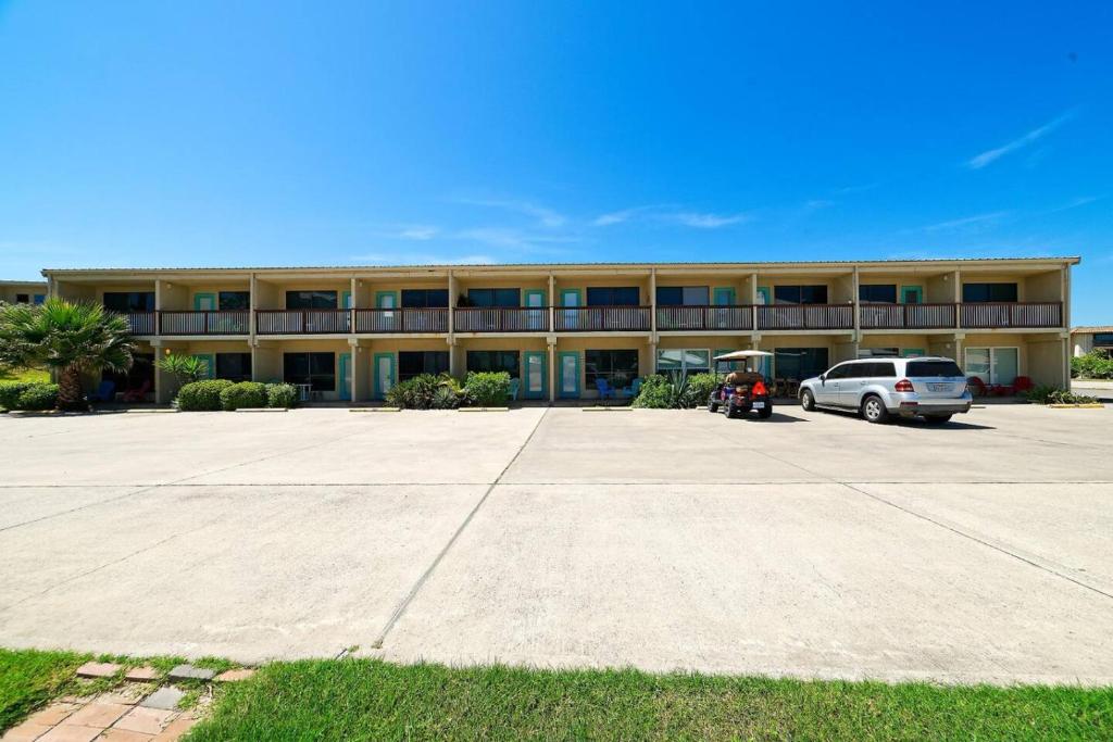 a large building with a car parked in a parking lot at Five O Clock Somewhere in Port Aransas