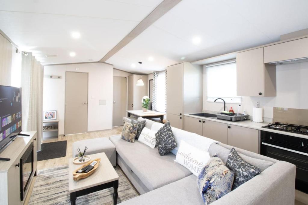 a living room with a white couch and a kitchen at The Forest Lodge, Glen Eagles. in Auchterarder