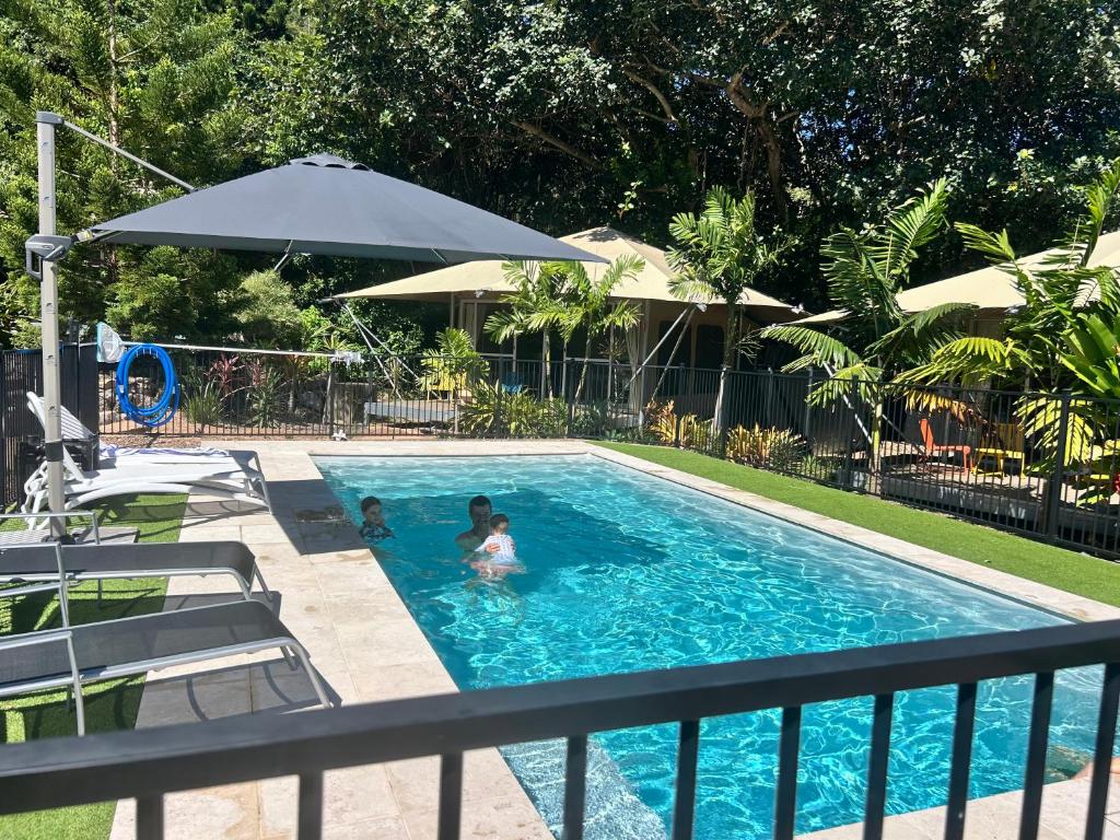 two people in a swimming pool with an umbrella at Magnetic Glamping in Nelly Bay