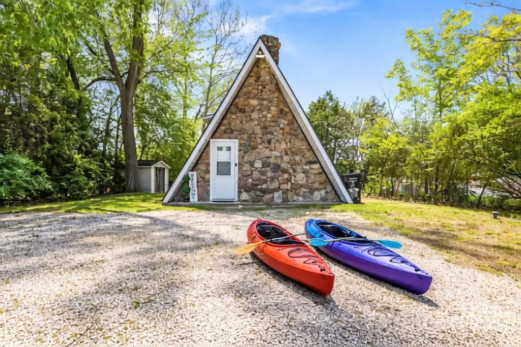 three kayaks on the ground in front of a small house at Romantic A-frame HeartJacuzzi Firepit Kayaks in Warsaw