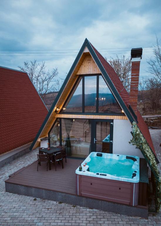 ein Haus mit einem Whirlpool auf einer Terrasse in der Unterkunft A-Frame Prislop,Hațeg in Silvaşu de Sus