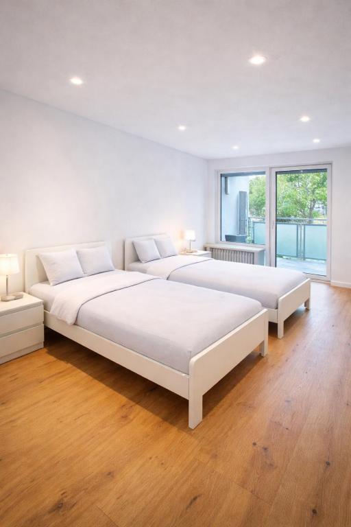 two beds in a white room with wood floors at Monteurunterkunft Frankenthal in Ormsheimerhof