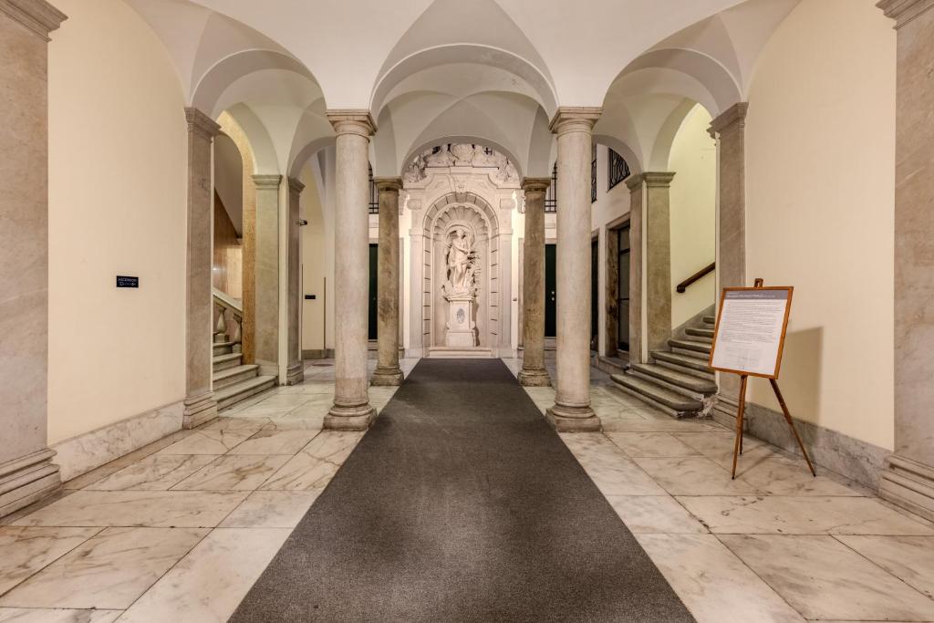 a hallway with columns and a sign in a building at Le Colonne Di San Luca Affittacamere in Genoa