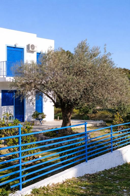 a blue fence with a tree in front of a building at Haraki Blue Houses in Haraki