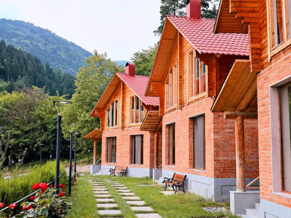 a row of brick buildings with benches in the grass at Eko cottages in Borjomi