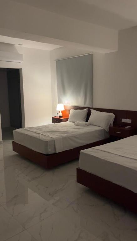 a bedroom with two beds and a table with a lamp at RUKA Hotel in Punta Cana