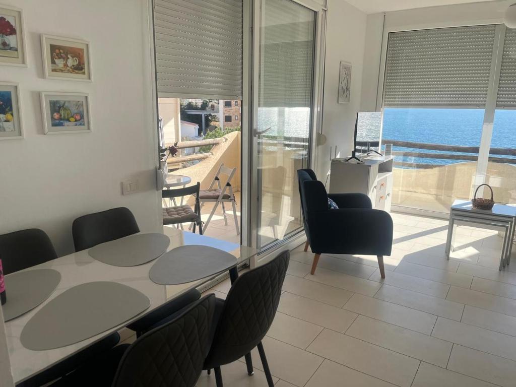a living room with a table and chairs and a balcony at Apartment bay, Bougainville Bay Resort in Sarandë