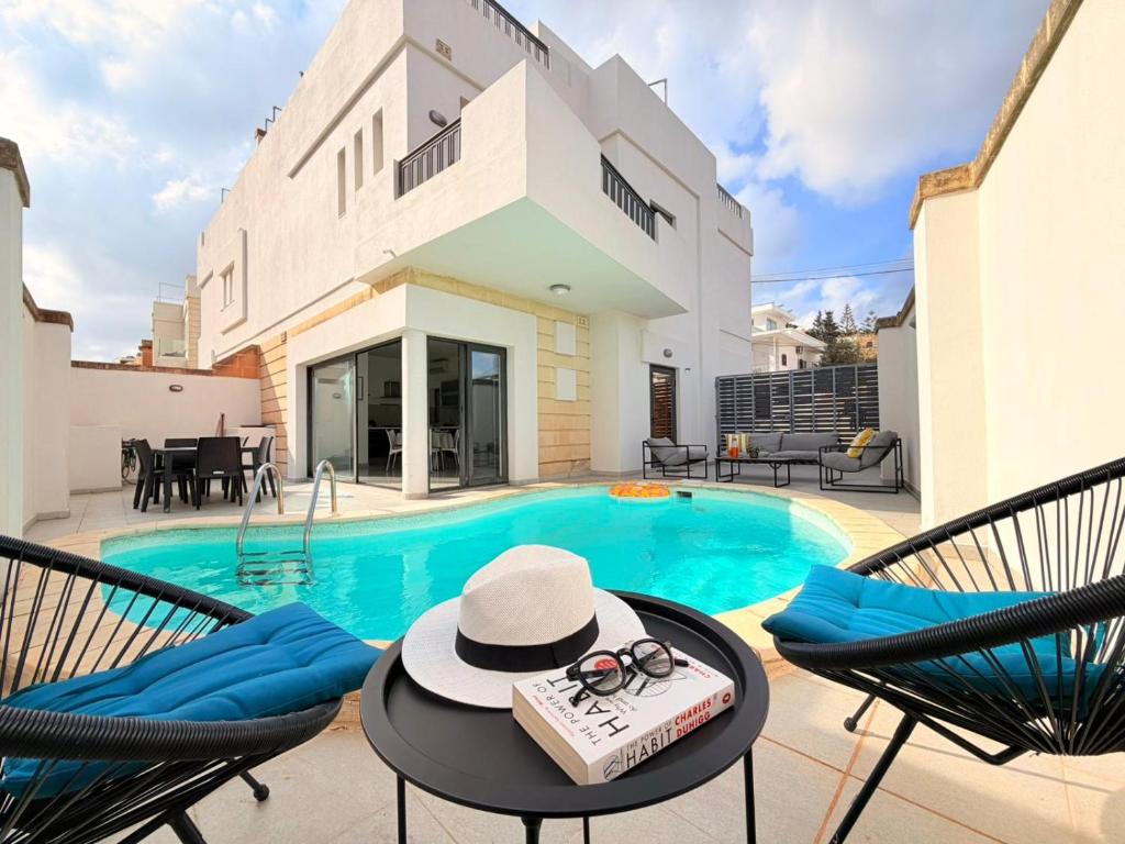 a house with a swimming pool with a table and chairs at Ultimate Group Getaway Near St Julian's & Seafront in San Ġwann