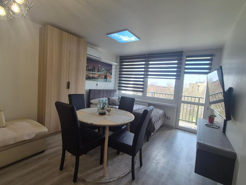 a living room with a table and chairs and a bedroom at Apartament Gliwice Centaura, dwa pokoje, klimatyzacja in Gliwice