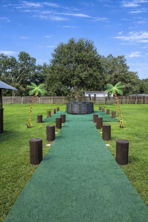 a green path with wooden stools on the grass at Family Country Retreat w Pool, Games & Fire Pit in Clewiston