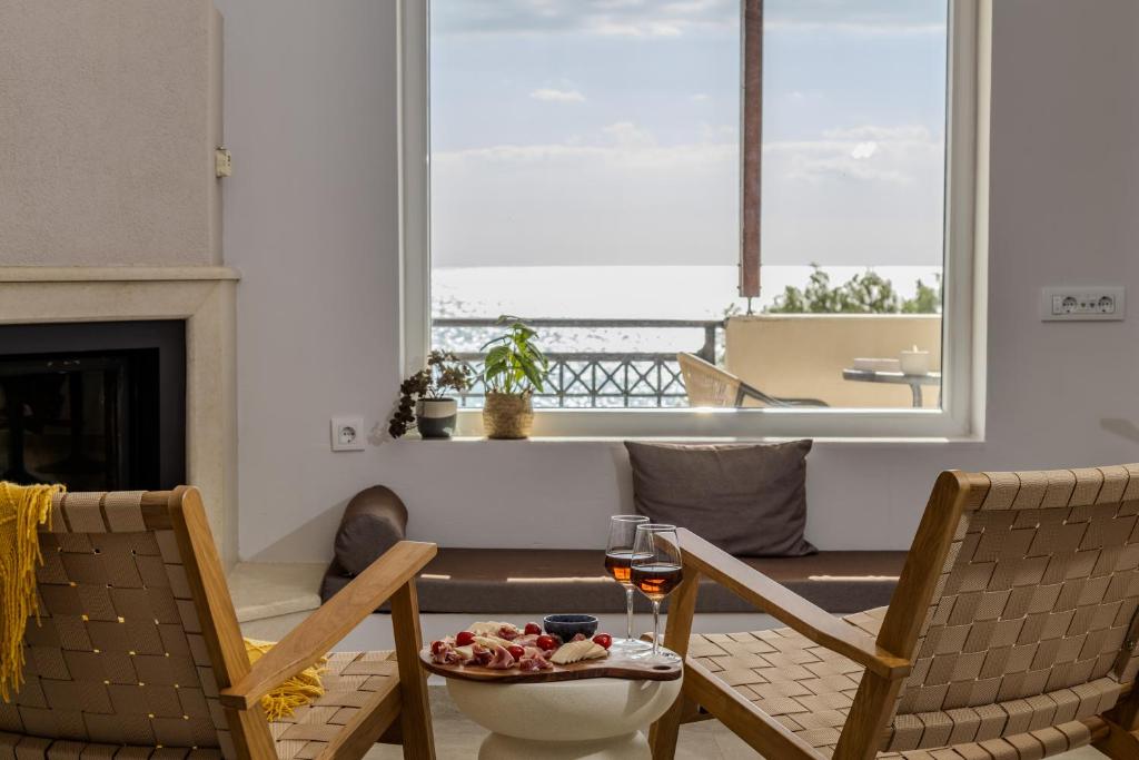 a living room with two chairs and a table with a glass of wine at Golden Horizon seafront in Goúdhouros