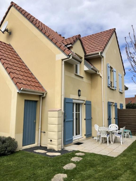 a house with blue doors and a table and chairs at Cottage en baie in Cayeux-sur-Mer