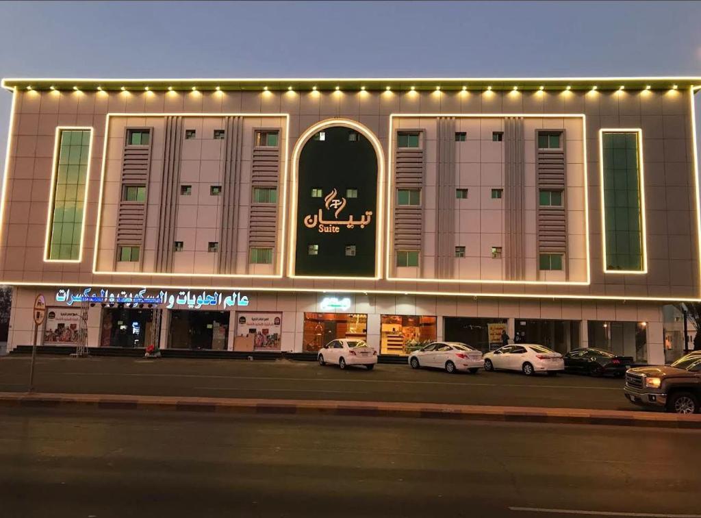 a large building with cars parked in a parking lot at شقق تبيان سويت للشقق المخدومة الفرع الاول in Ar Ruwanah