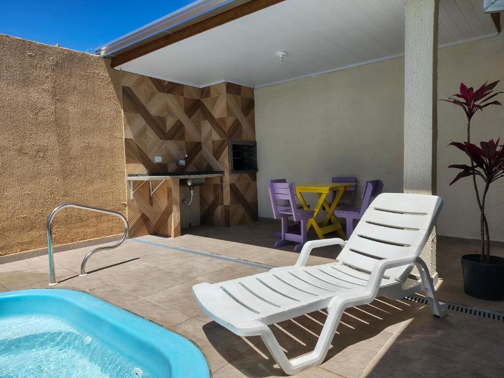 a pool with a chair and a tub on a patio at Oásis - Casa com Piscina e Churrasqueira in Pontal do Paraná
