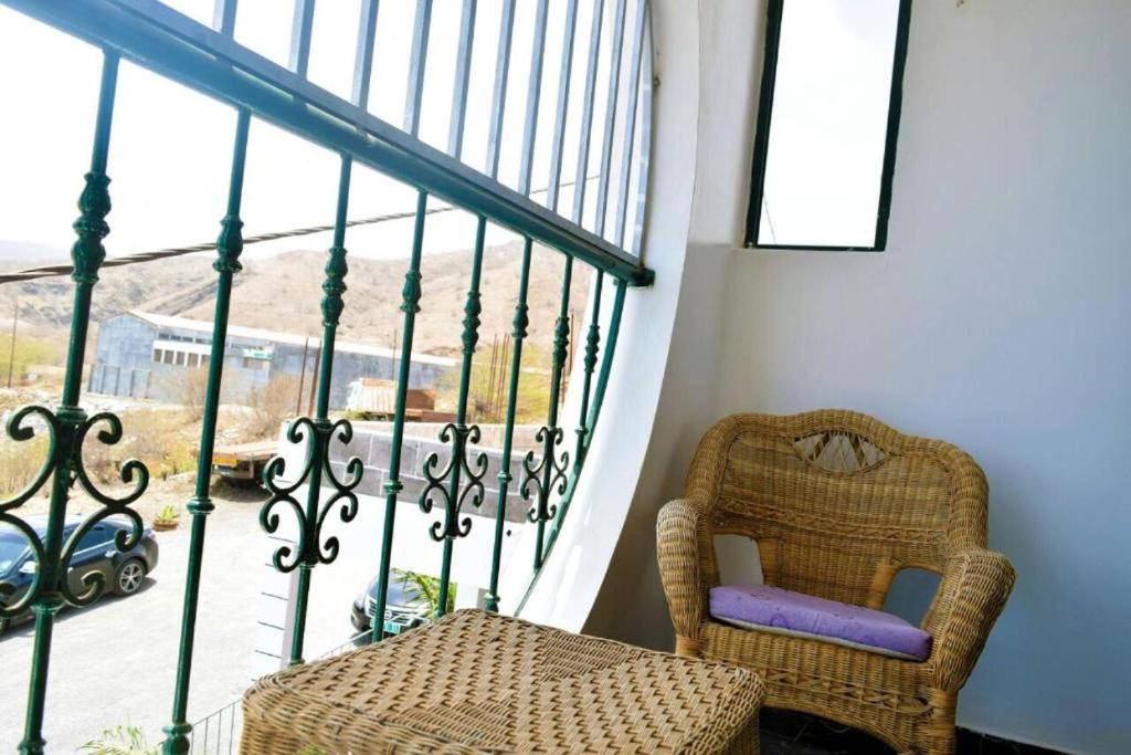 a room with a chair and a balcony with a view at Fogo Island in São Filipe