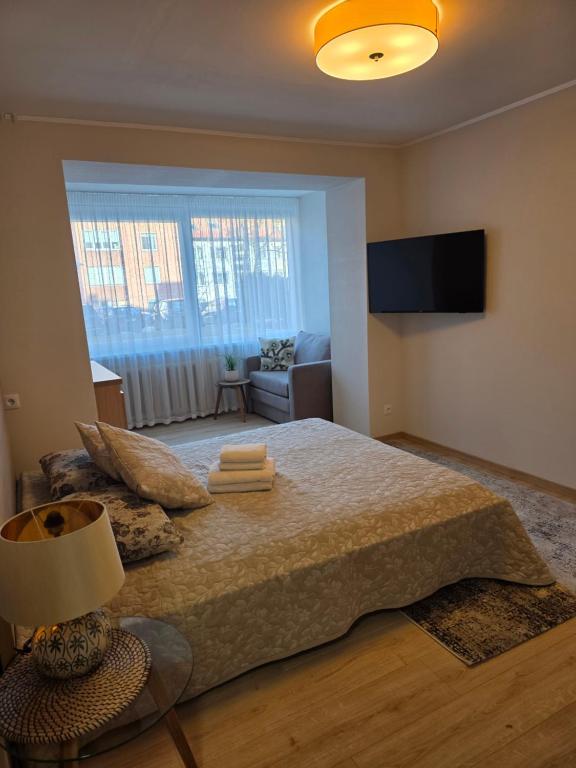 a bedroom with a bed with a lamp and a couch at Nidos centras -Taikos g in Nida