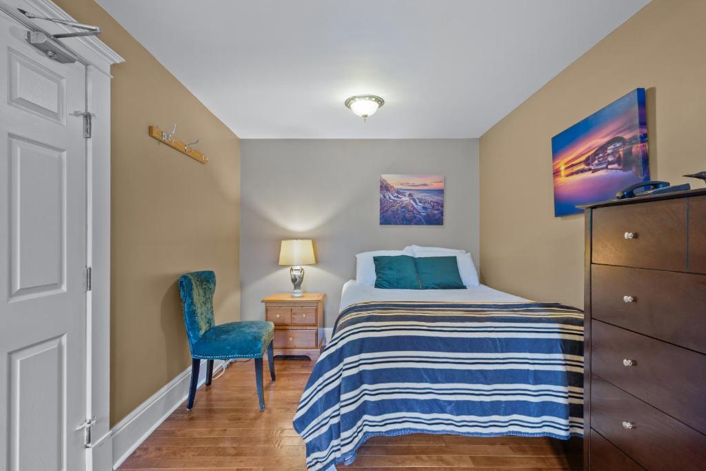 a small bedroom with a bed and a blue chair at Chic Midstream Studio WiFi Parking in St. John's