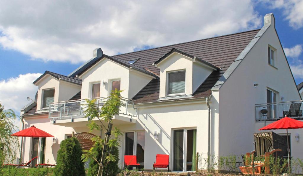 a white house with red chairs in front of it at Villa Harmonie W2 in Göhren-Lebbin