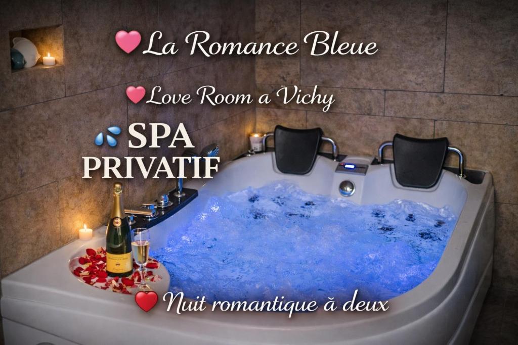 a bath tub filled with blue water in a bathroom at Romance Bleue -Love Room -SPA privatif - Netflix -séjour à vichy in Vichy
