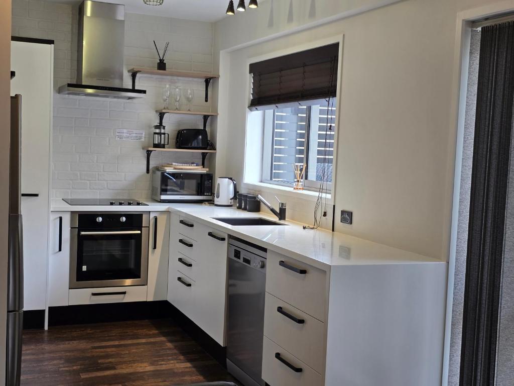 a kitchen with white cabinets and a sink and a window at City Living in New Plymouth