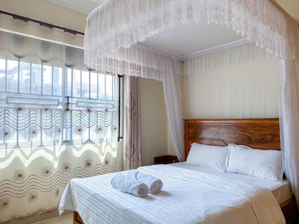 a bedroom with a white bed with a window at NL Josephine's Hotel, Apartment in Kampala