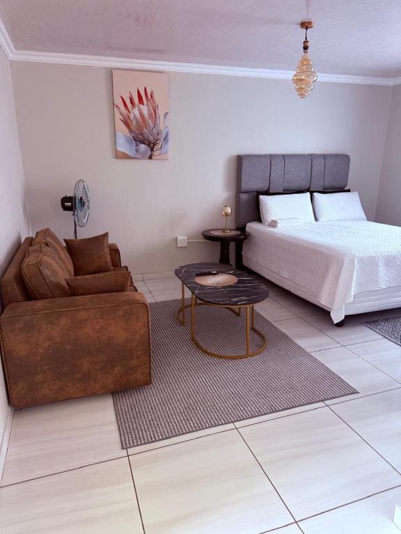 a bedroom with a bed and a couch and a table at Ella Guest House in Pretoria
