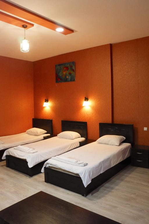 two beds in a room with orange walls at Diuma 5 Guest house in Tbilisi City