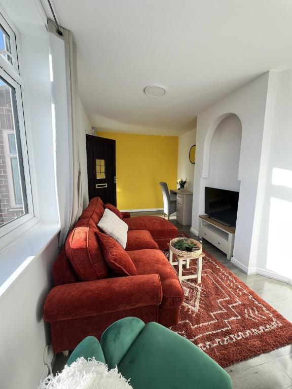 a living room with two red couches and a tv at Two Bedroom Flat Bristol in Shirehampton