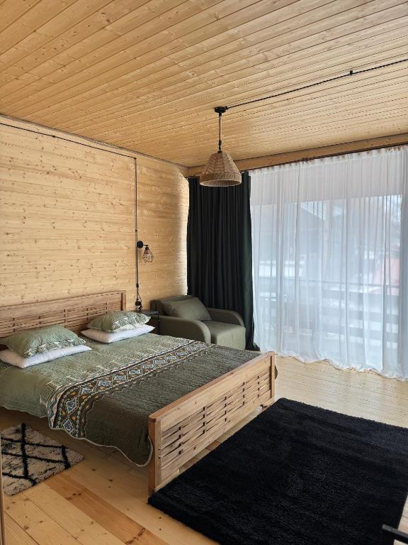 a bedroom with a bed and a chair in a room at Tetri Jikhvi in Kazbegi