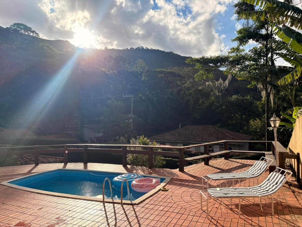 a patio with two chairs and a swimming pool at Refúgio Carangola in Petrópolis