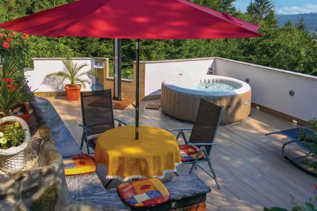 a deck with a hot tub and a red umbrella at Forest Retreat Bonidesa - Terrace & Jacuzzi - Happy Rentals in Ljubno